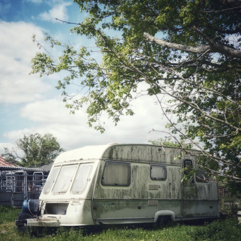 Decaying caravan and rusty farm sheds